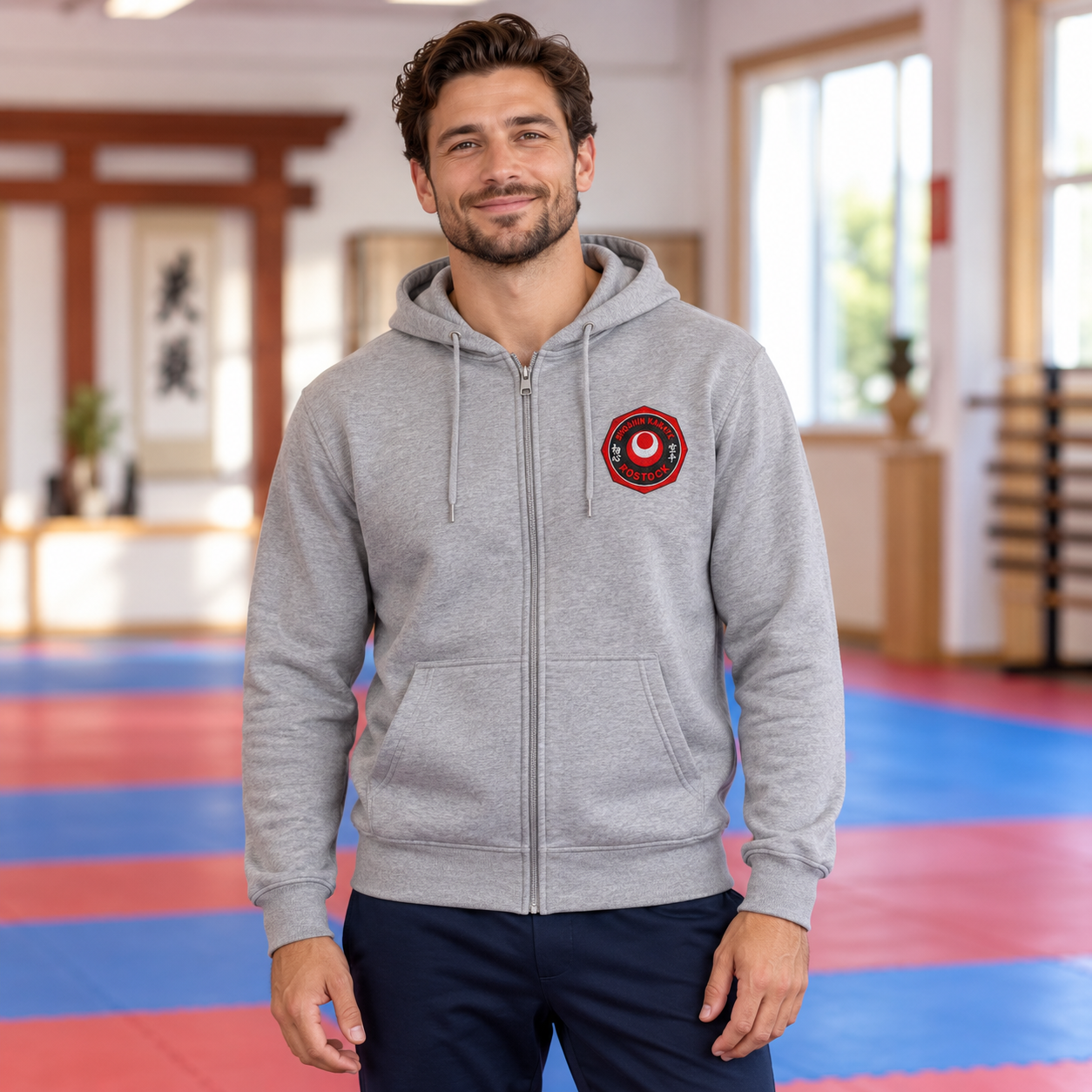  Mann trägt eine grau melierte Kapuzenjacke mit Reißverschluss und ShoShin-Logo auf der linken Brustseite